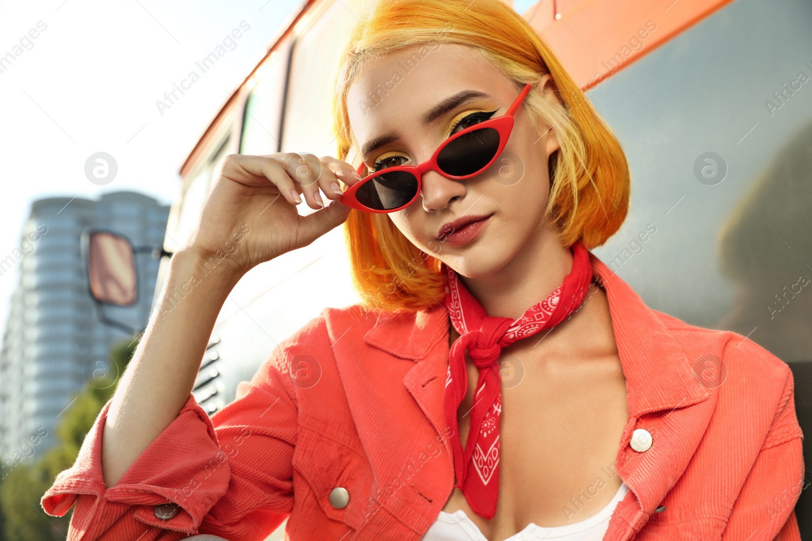 Photo of Beautiful young woman with bright dyed hair in sunglasses outdoors