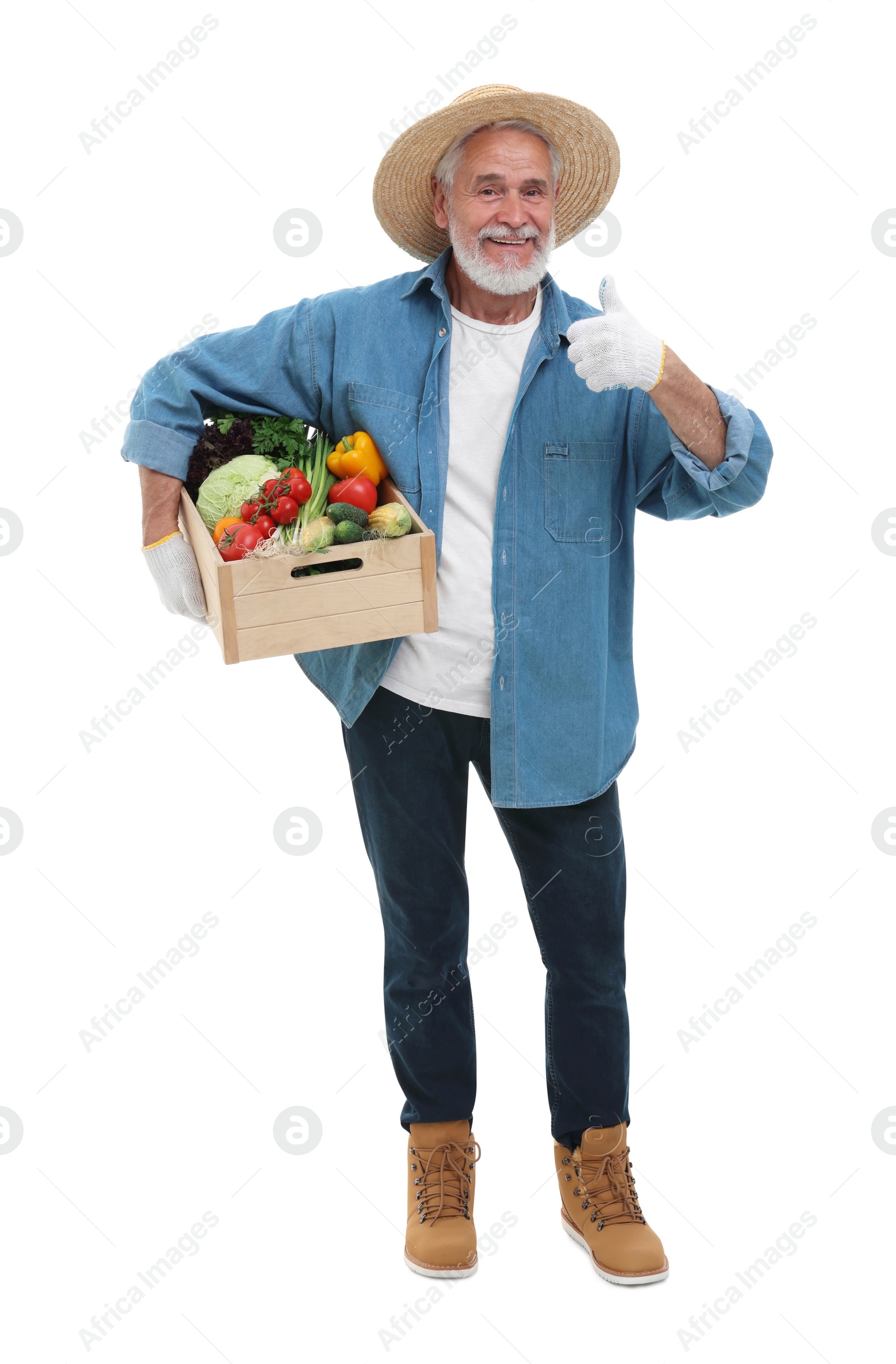 Photo of Harvesting season. Happy farmer holding wooden crate with vegetables and showing thumb up on white background