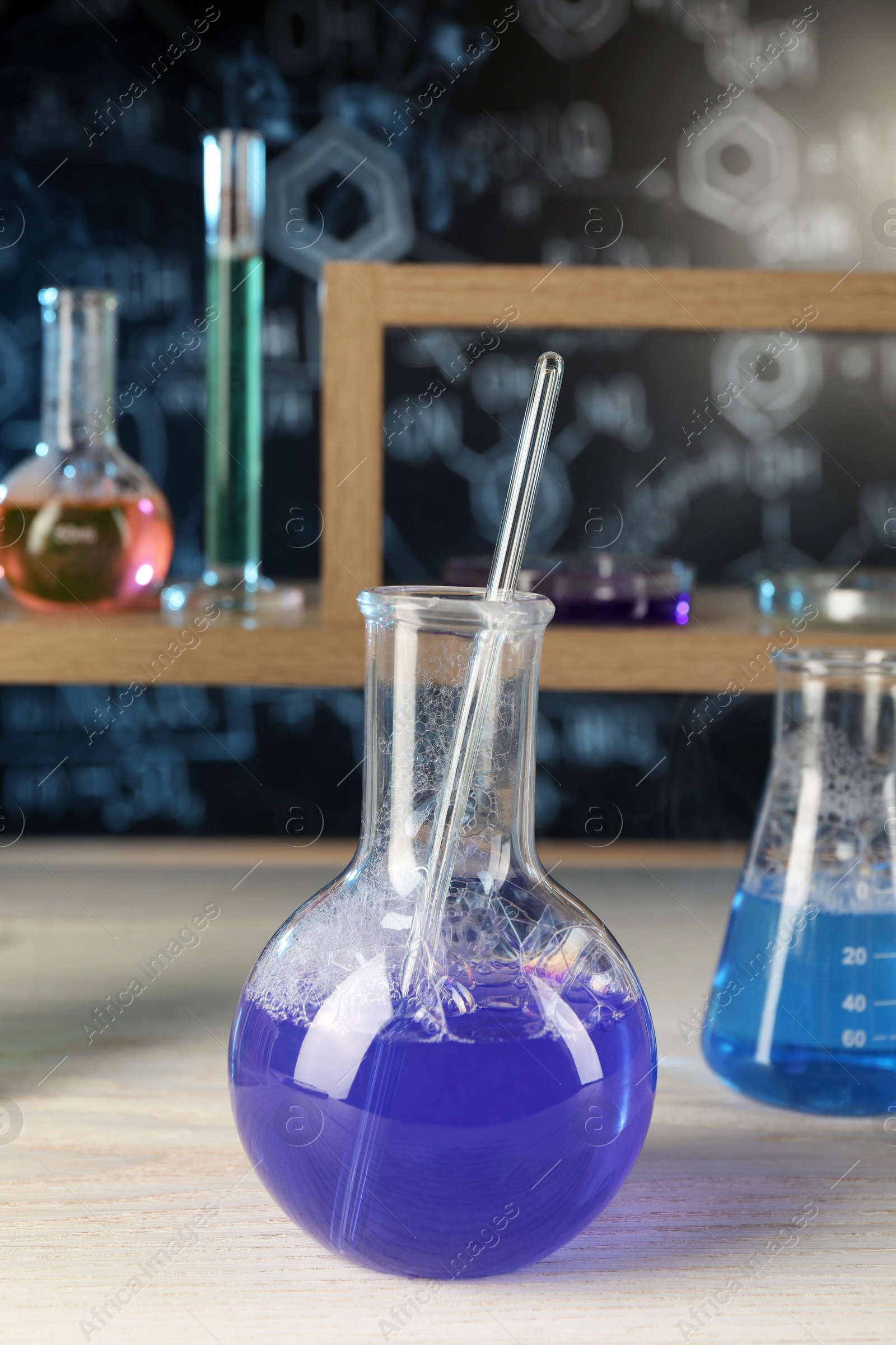 Photo of Laboratory glassware with blue liquid on white wooden table, space for text. Chemical reaction