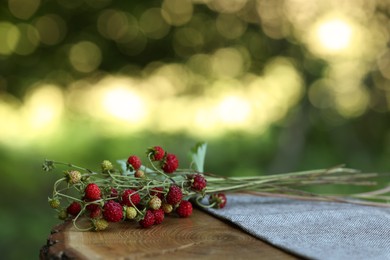 Photo of Bunch with tasty wild strawberries on wooden stump outdoors. Space for text