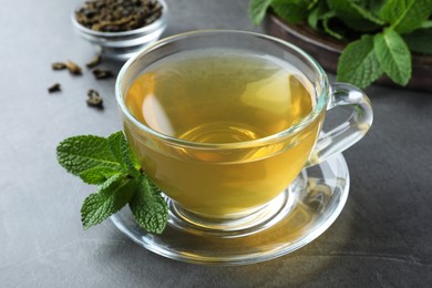 Cup of hot aromatic mint tea on grey table, closeup