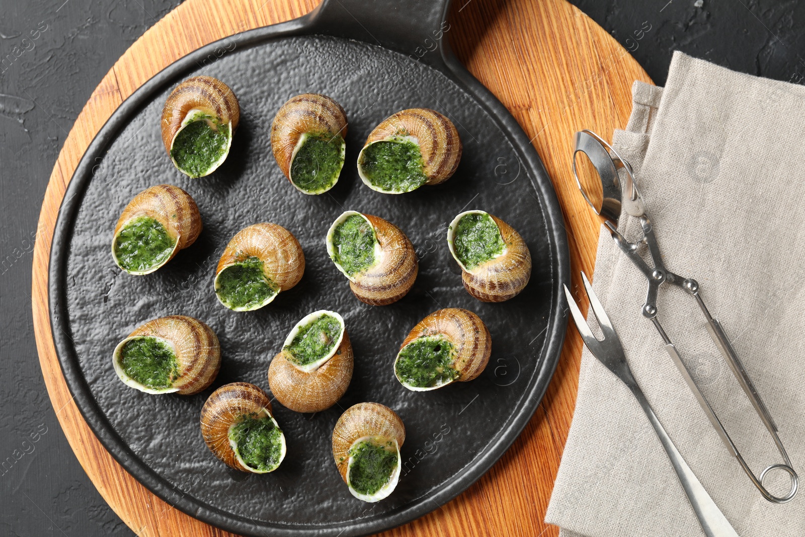 Photo of Delicious cooked snails served on grey textured table, flat lay