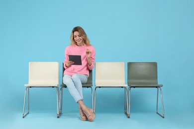 Photo of Young woman with tablet waiting for job interview on light blue background