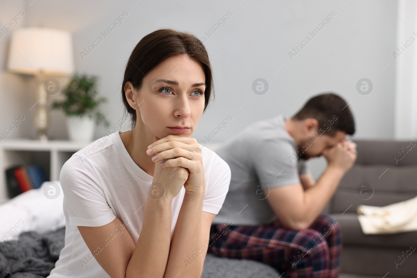 Photo of Offended couple ignoring each other after quarrel in bedroom, selective focus. Relationship problems