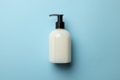 Bottle of liquid soap on light blue background, top view