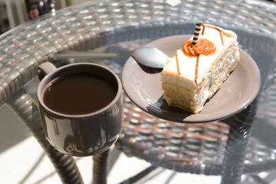 Photo of Tasty dessert and cup of fresh aromatic coffee on glass table outdoors