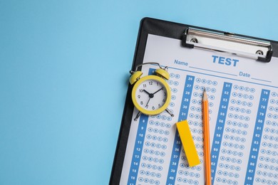 Photo of Student passing exam. Clipboard with answer sheet, pencil and alarm clock on light blue background, top view. Space for text.