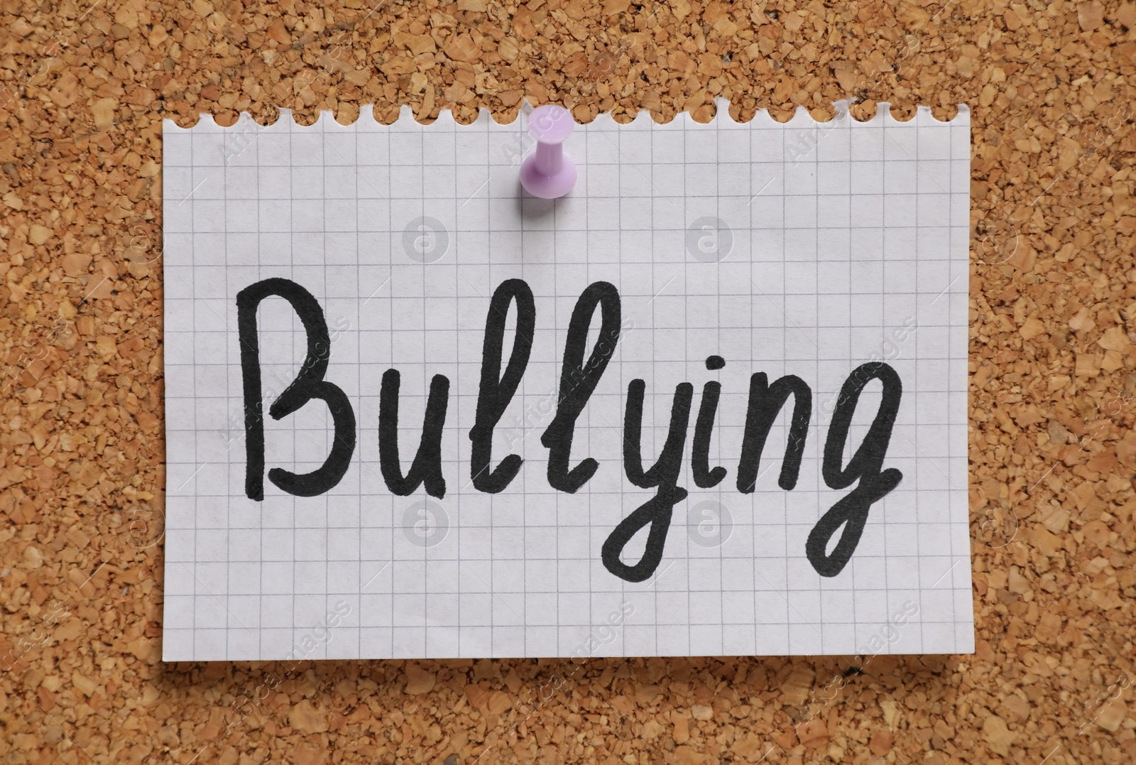 Photo of Note with phrase Stop Bullying pinned to cork board, closeup