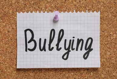 Photo of Note with phrase Stop Bullying pinned to cork board, closeup