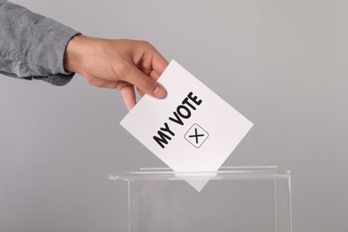 Man putting paper with text My Vote and tick into ballot box on light grey background