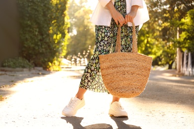 Young woman with stylish straw bag in park, closeup