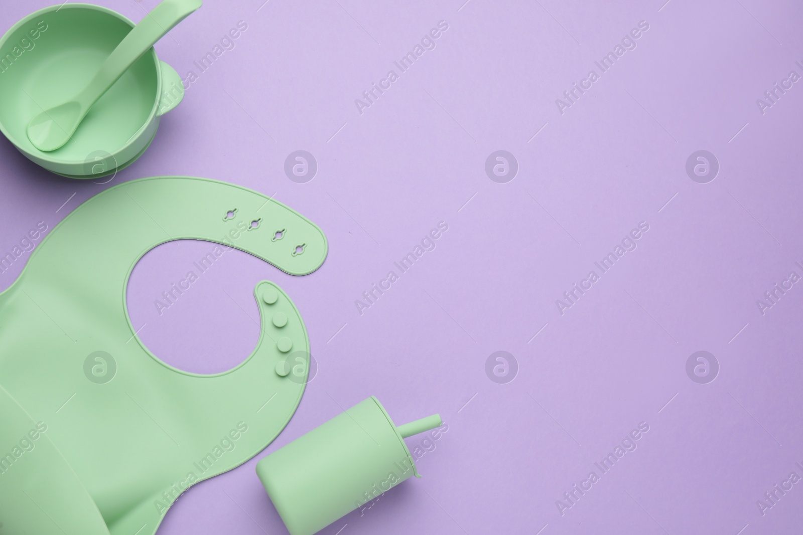 Photo of Flat lay composition with baby feeding accessories and bib on violet background, space for text