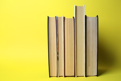 Collection of hardcover books on yellow background, space for text