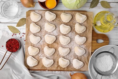 Photo of Raw dumplings (varenyky) with tasty filling and ingredients on white wooden table, flat lay