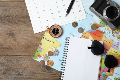 Flat lay composition with world map and different travel accessories on wooden table. Planning summer vacation trip