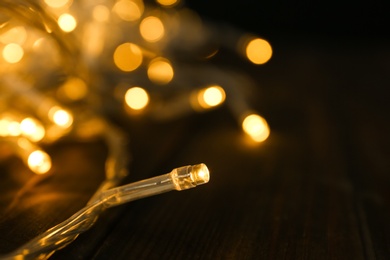 Photo of Glowing Christmas lights on table, closeup view