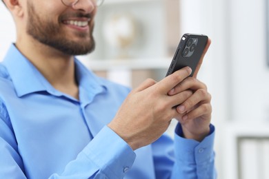 Photo of Young man using smartphone in office, closeup