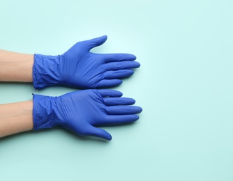 Photo of Person in medical gloves on light blue background, top view. Space for text