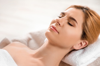 Beautiful woman with silky skin after face mask relaxing in spa salon