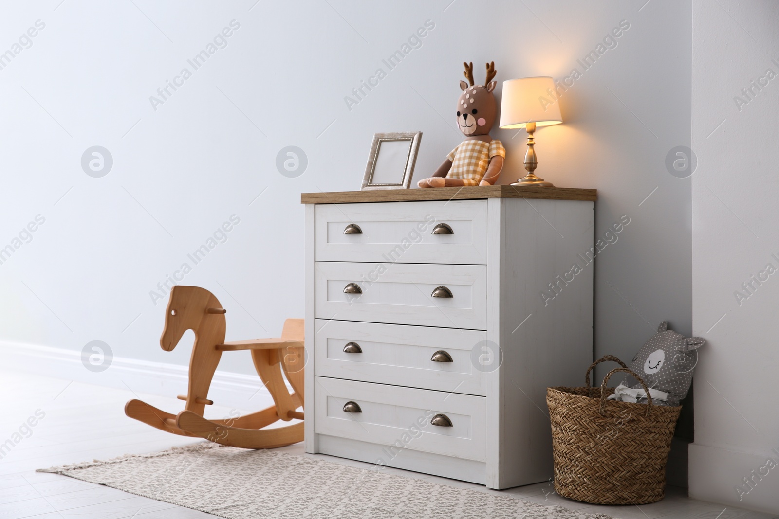 Photo of Modern white chest of drawers near light wall in child room. Interior design