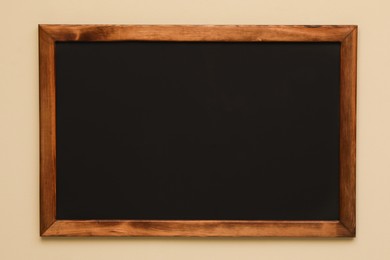 Clean black chalkboard hanging on beige wall