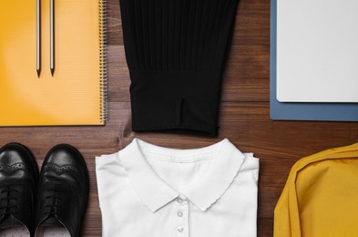 Stylish school uniform and stationery on wooden background, flat lay