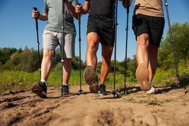 Photo of Men practicing Nordic walking with poles outdoors on sunny day, closeup