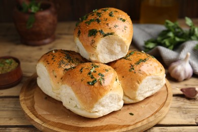 Photo of Traditional pampushka buns with garlic and herbs on wooden table