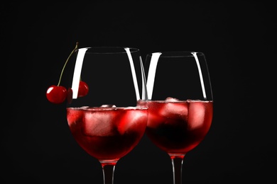 Delicious cherry wine with ripe juicy berries on black background, closeup