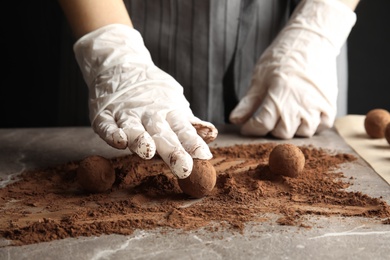 Photo of Woman preparing tasty chocolate truffles at table, closeup