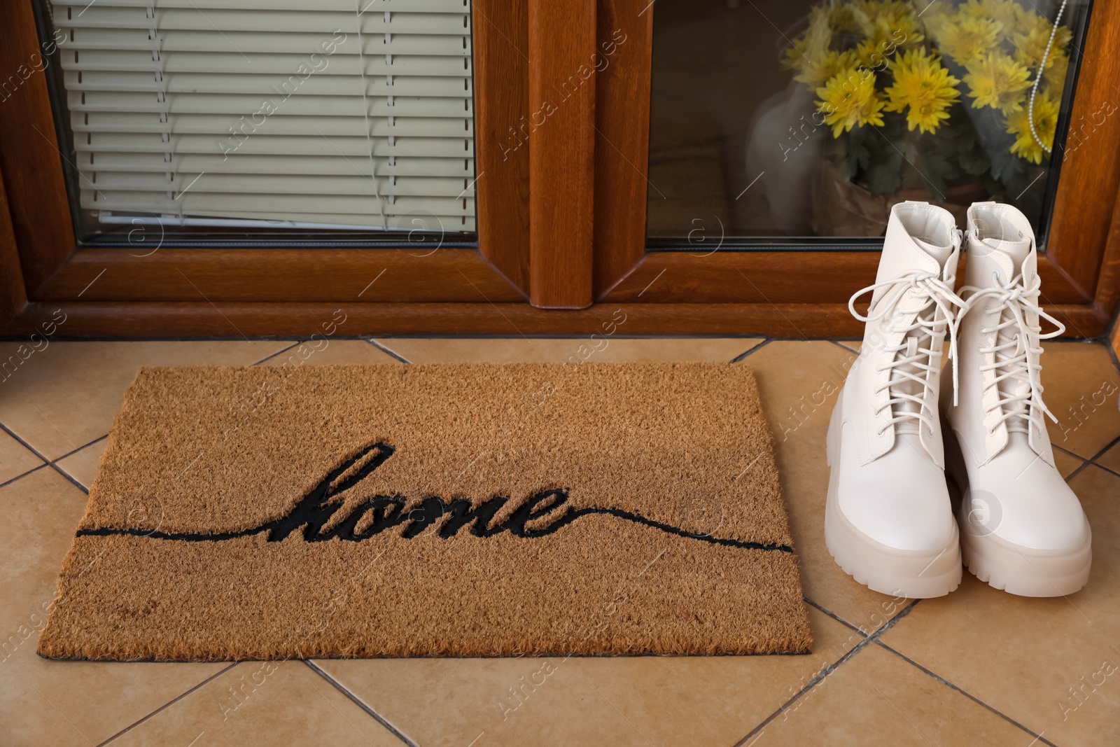 Photo of Doormat with word Home and stylish boots near entrance outdoors