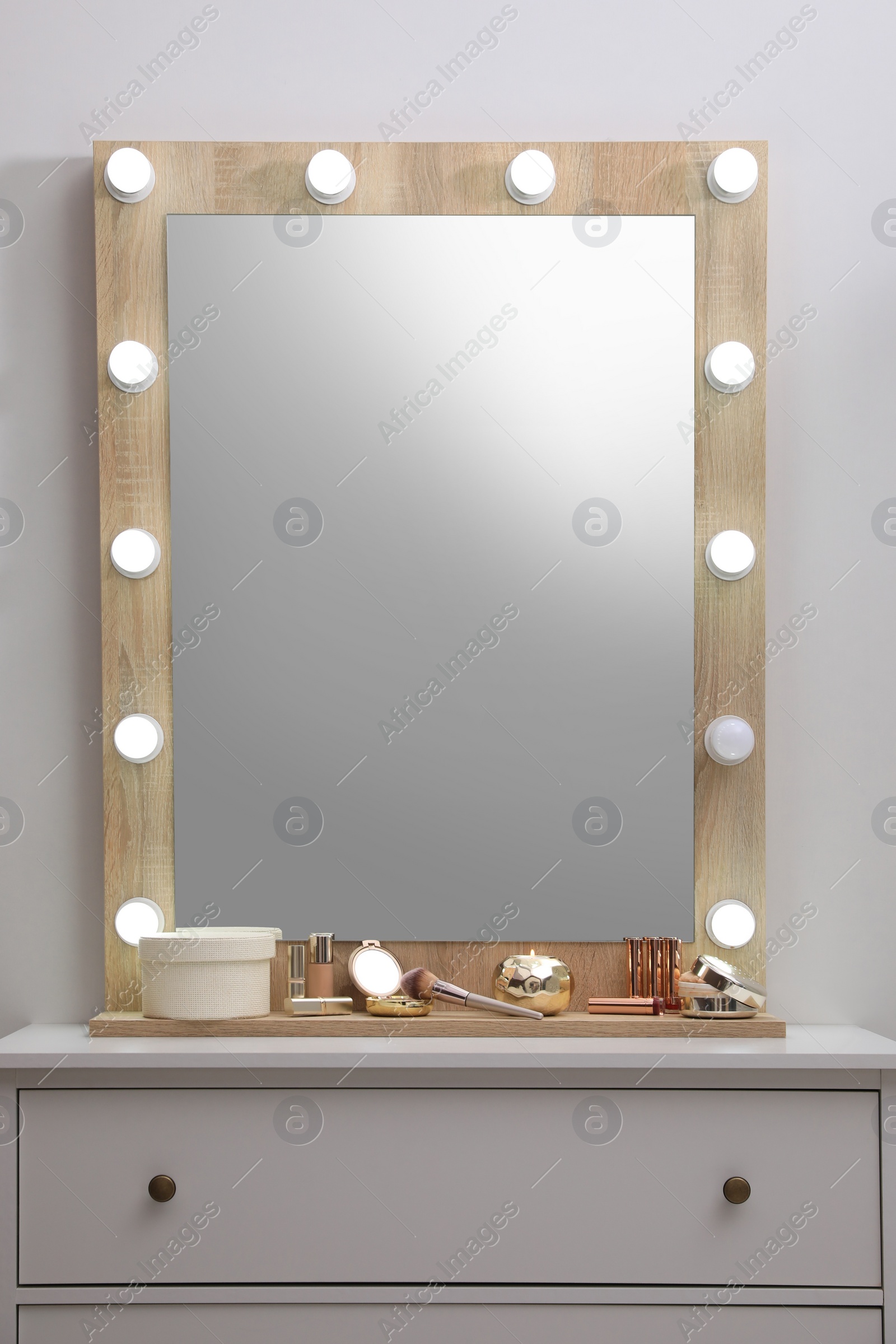 Photo of Stylish dressing table with cosmetics, mirror and accessories near white wall