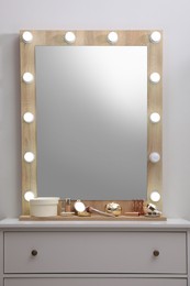 Photo of Stylish dressing table with cosmetics, mirror and accessories near white wall