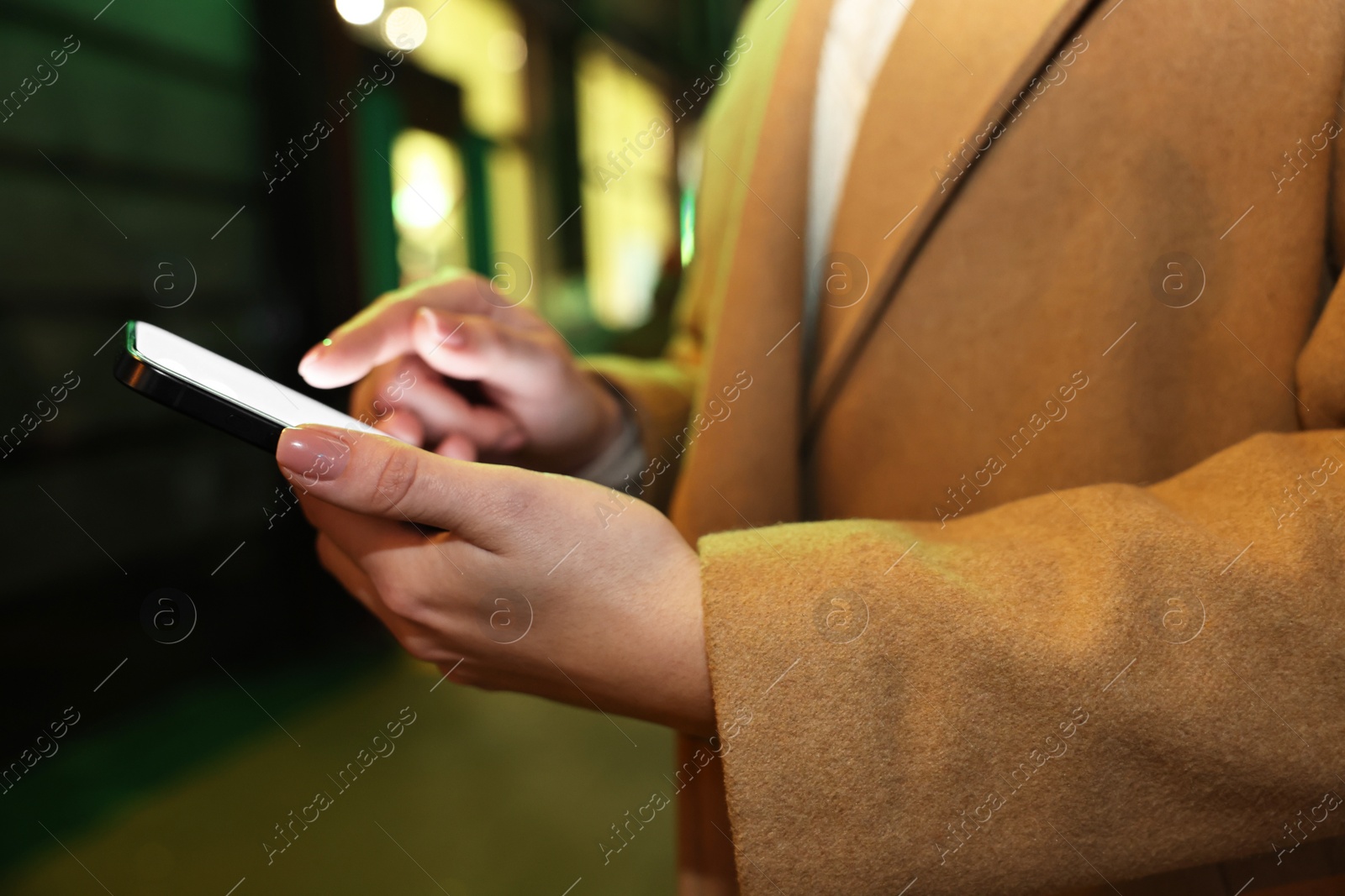 Photo of Woman using smartphone on night city street, closeup