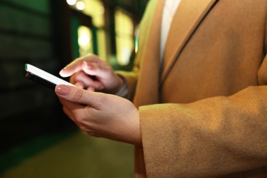 Photo of Woman using smartphone on night city street, closeup