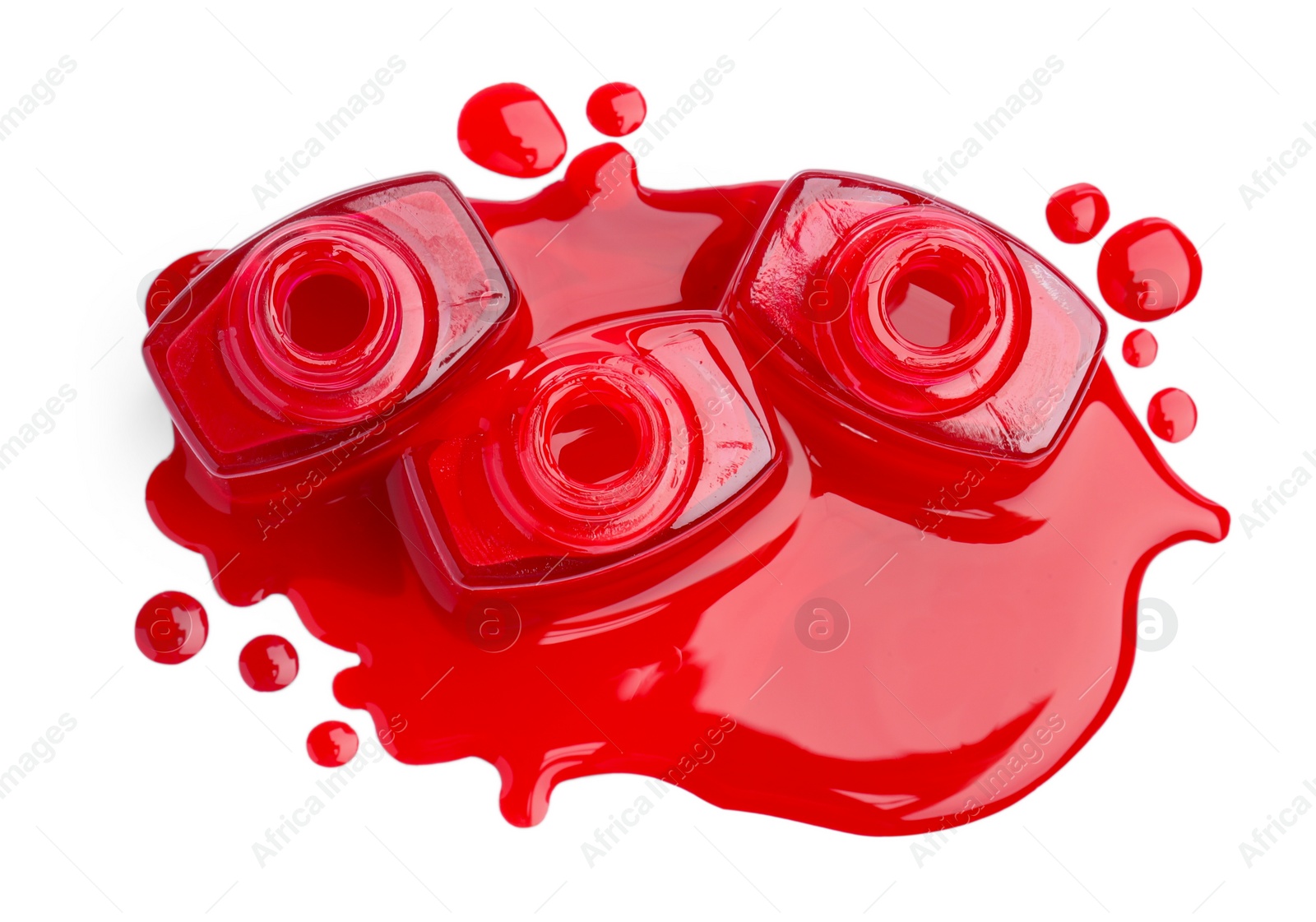 Photo of Puddle of red nail polish and bottles isolated on white, top view