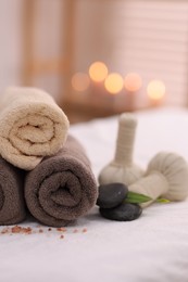 Spa stones, rolled towels and herbal bags on massage table indoors, closeup