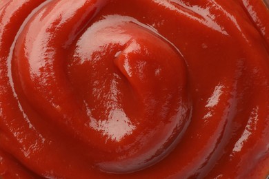 Tasty red ketchup as background, top view