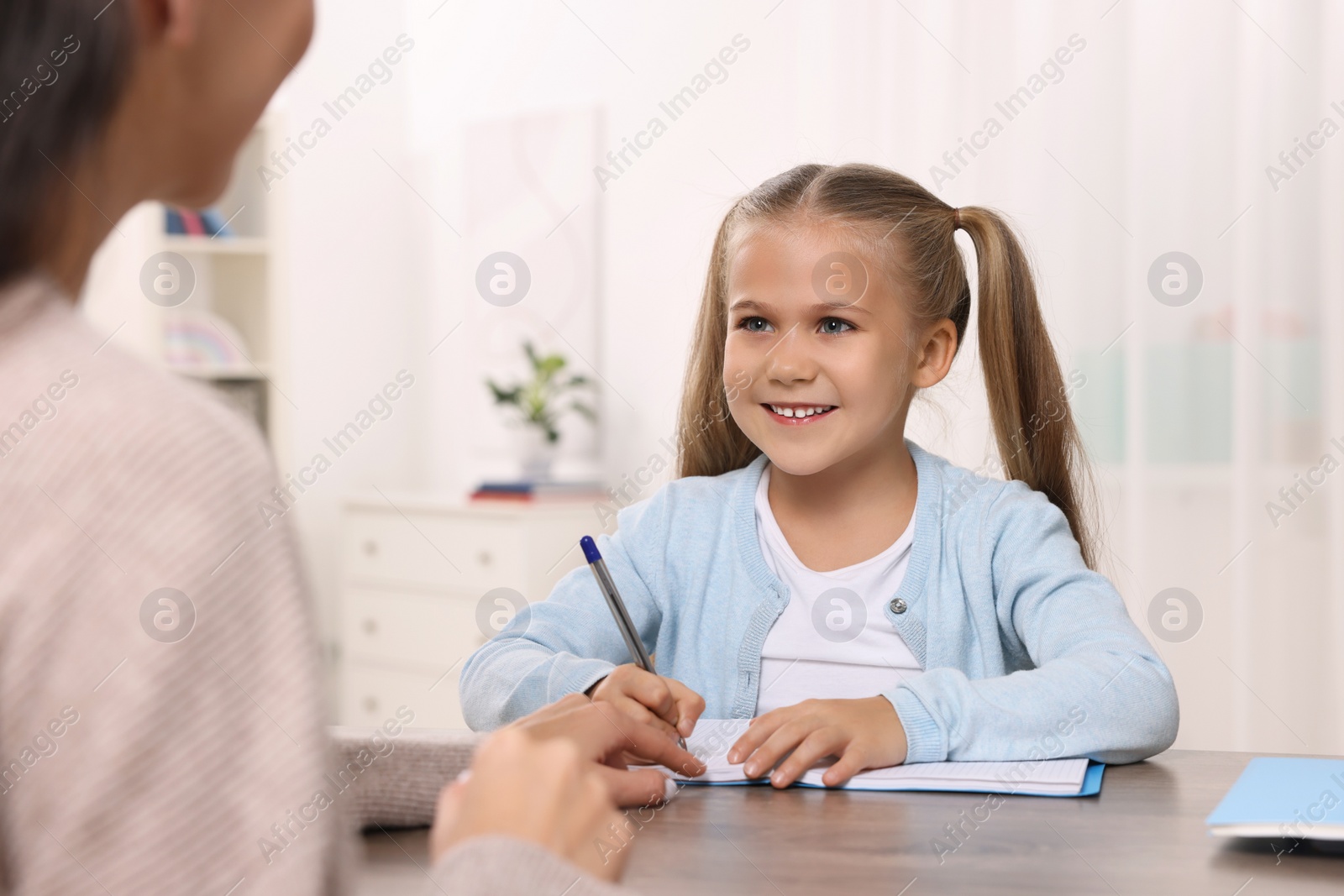 Photo of Dyslexia treatment. Therapist working with girl at table in room