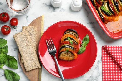 Photo of Delicious ratatouille with basil served on white marble table, flat lay