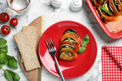 Delicious ratatouille with basil served on white marble table, flat lay