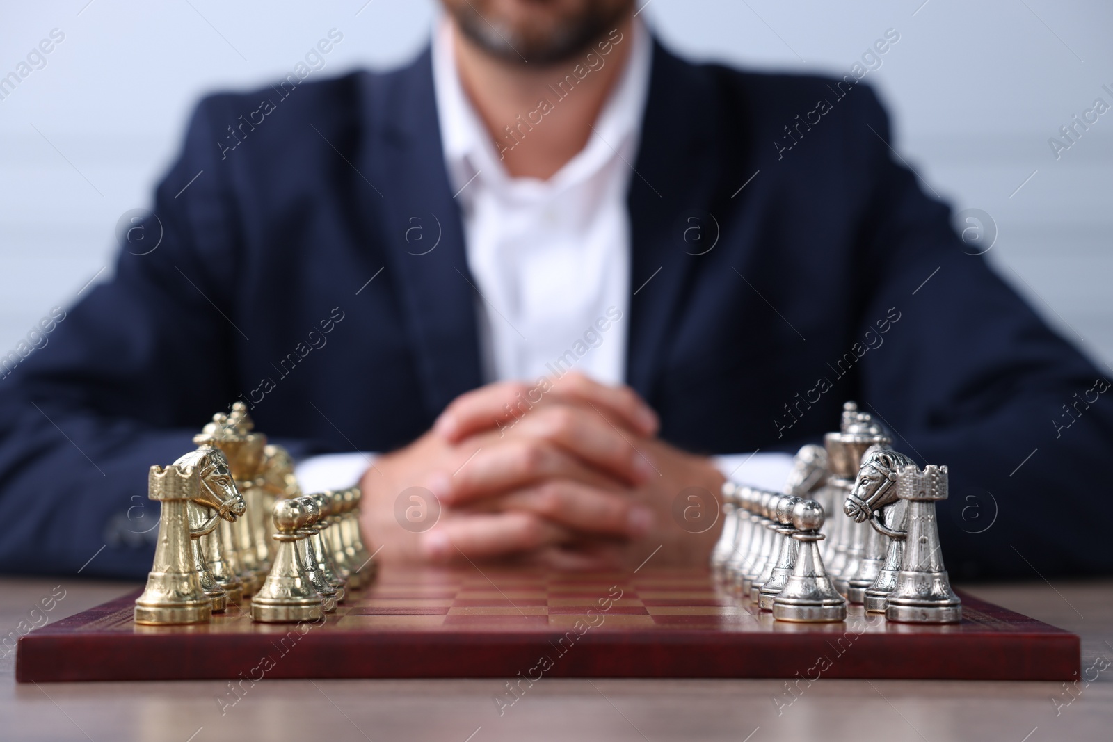 Photo of Man with chess pieces on checkerboard at table before game, closeup