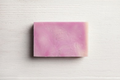 Hand made soap bar on white wooden background, top view