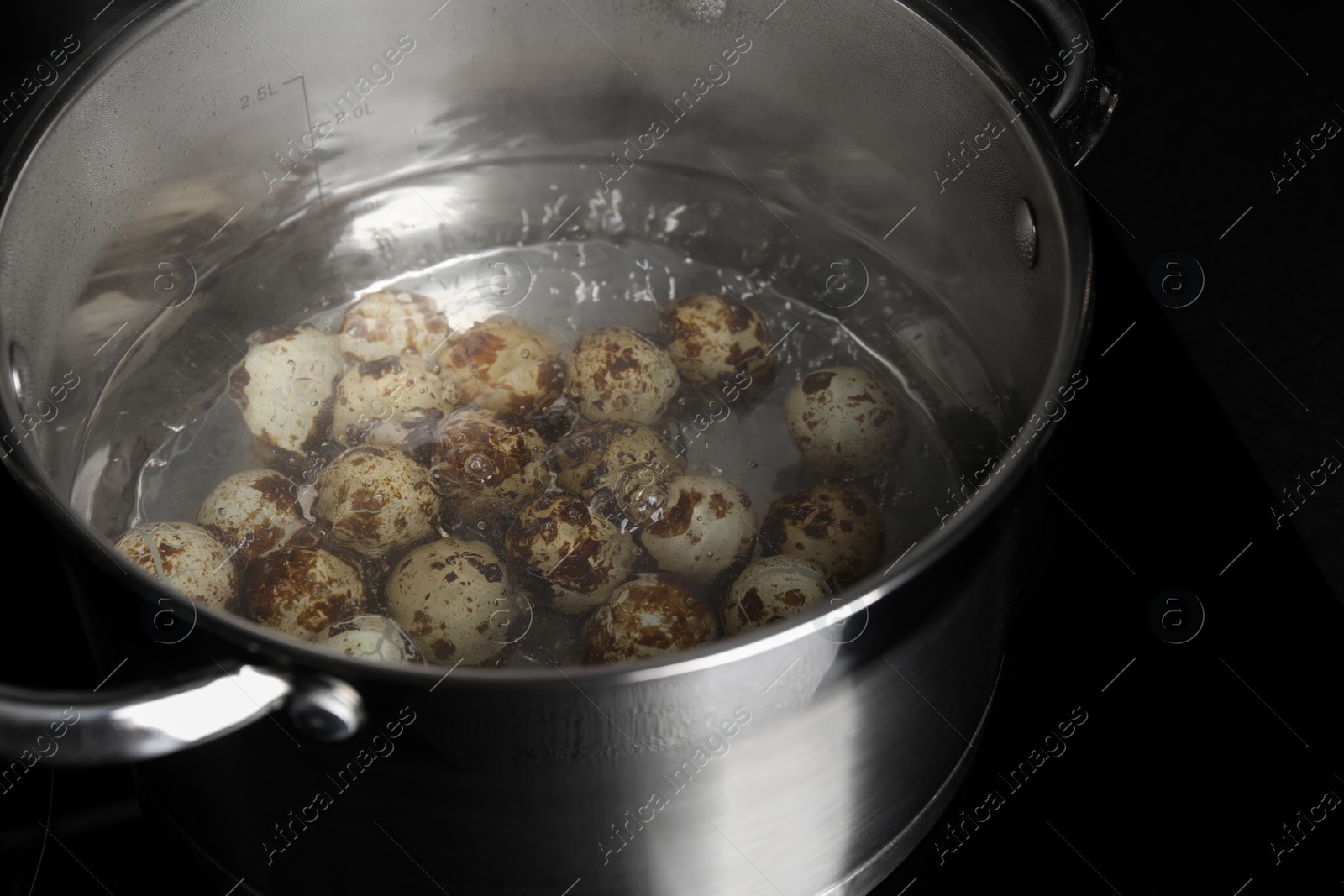 Photo of Cooking quail eggs in pot on electric stove, closeup