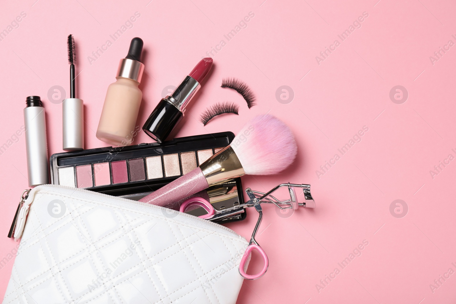 Photo of Cosmetic bag and makeup products with accessories on pink background, flat lay. Space for text