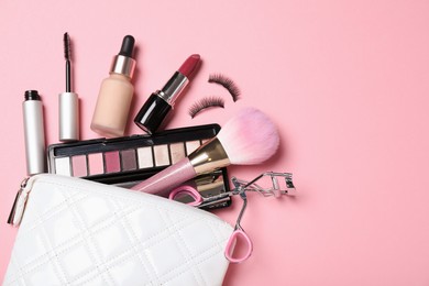 Cosmetic bag and makeup products with accessories on pink background, flat lay. Space for text