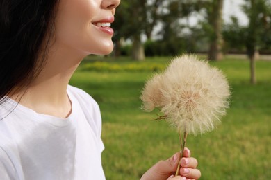 Photo of Beautiful young woman with large dandelions in park, closeup. Allergy free concept