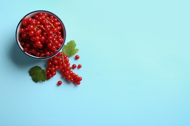 Photo of Delicious red currants and leaves on light blue background, flat lay. Space for text