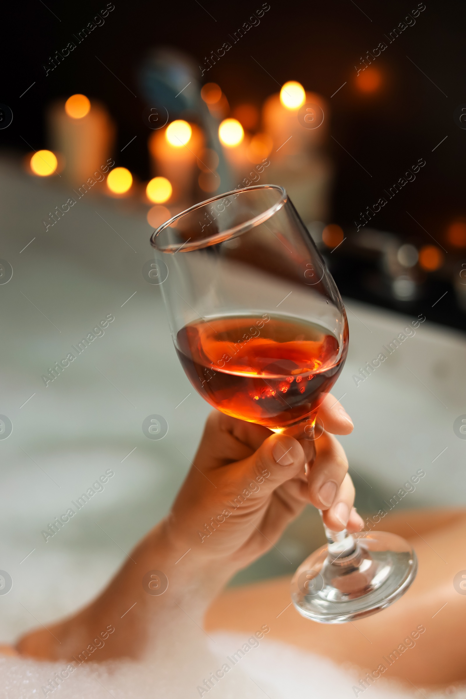 Photo of Woman drinking wine while taking bubble bath, closeup. Romantic atmosphere