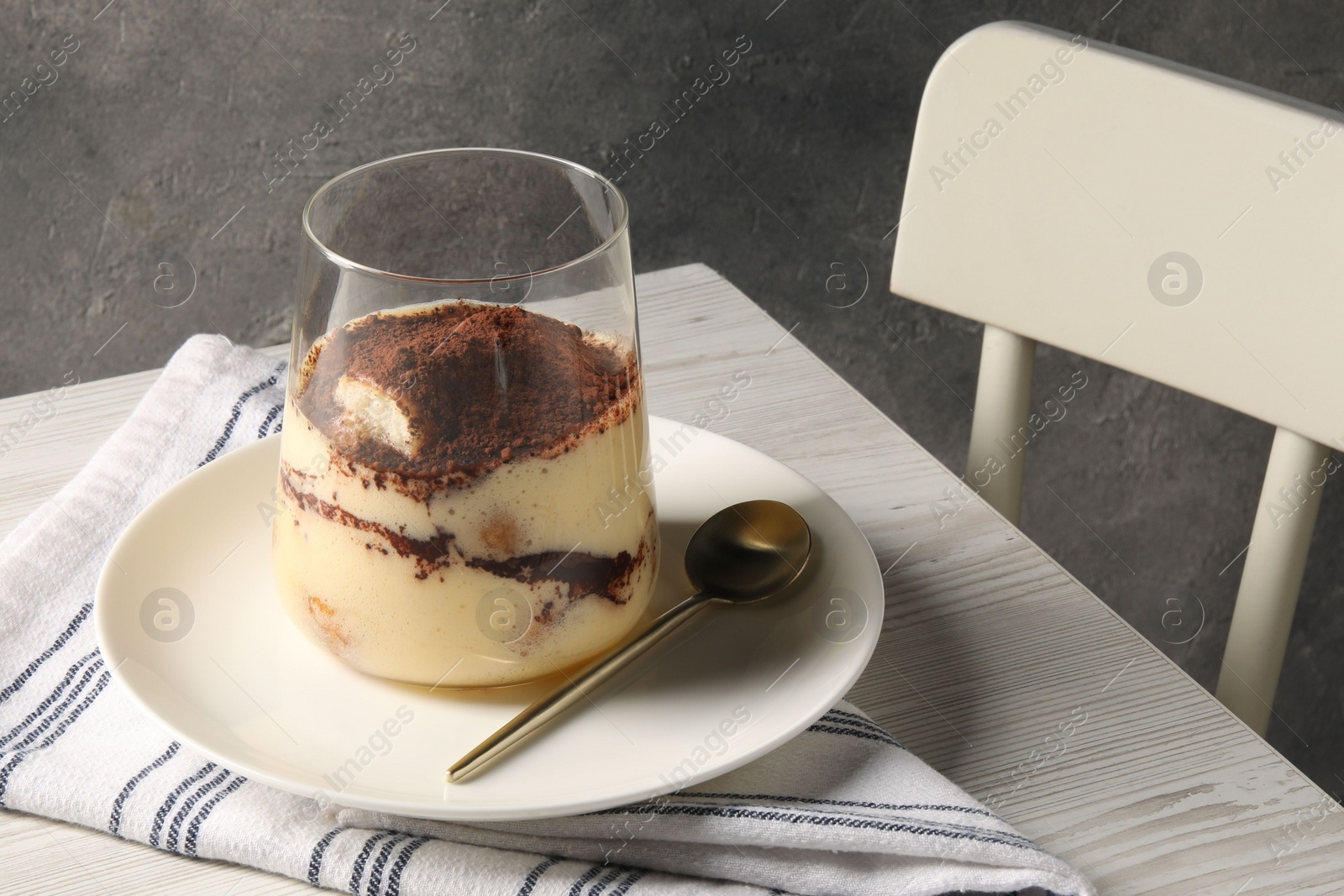 Photo of Delicious tiramisu in glass on white wooden table